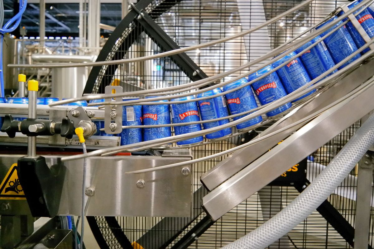 Cerveza en una rejilla plateada bajando una línea de producción
